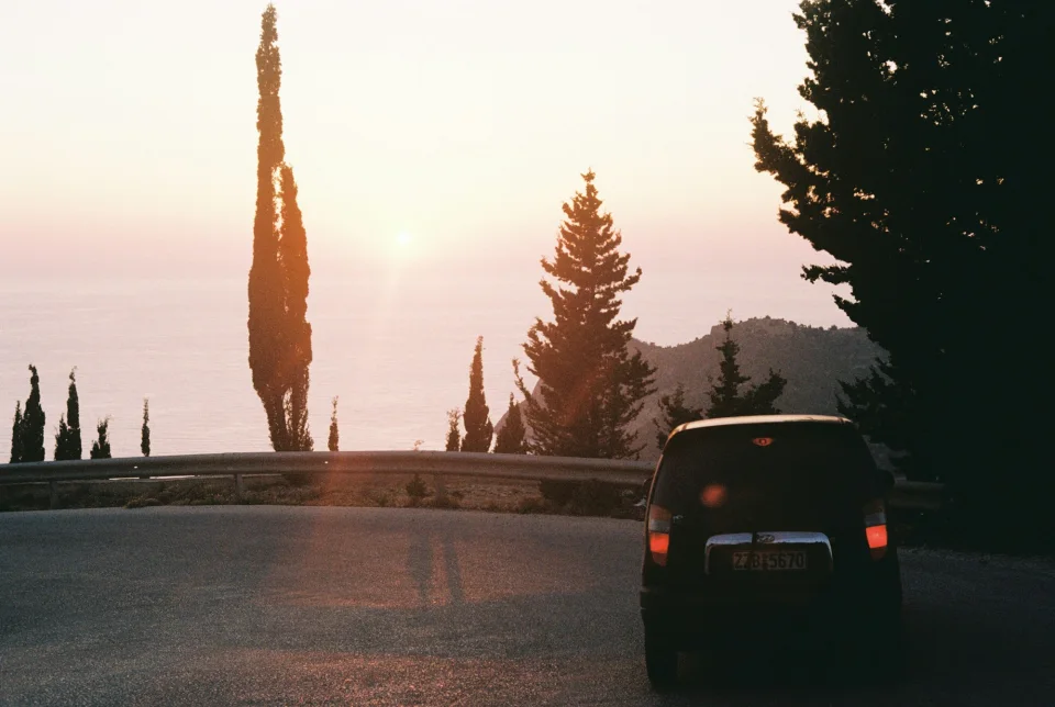A car on a coastal road at sunset in Kefalonia, Greece
